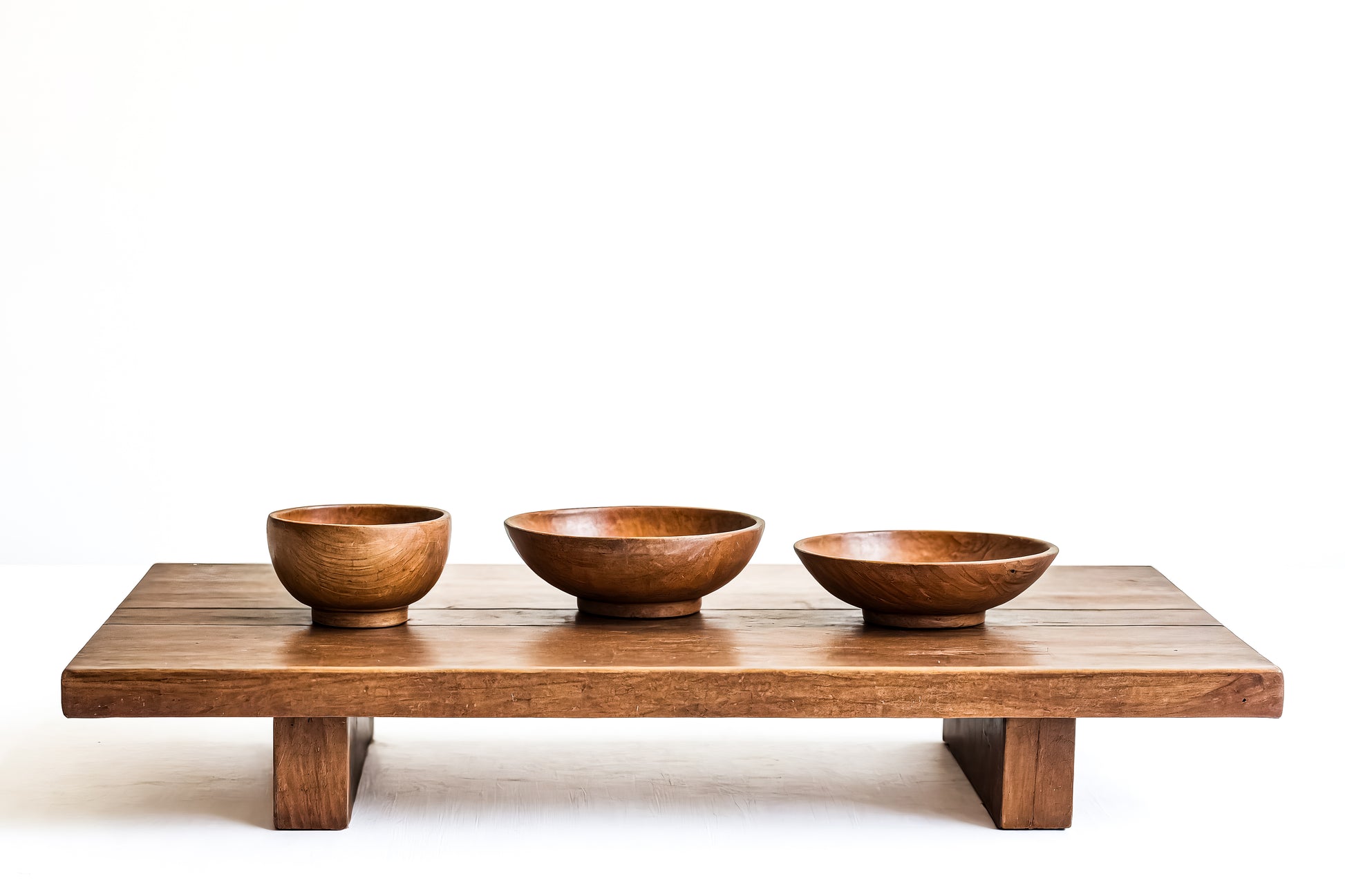 Three wooden bowls on a wooden table with a white background