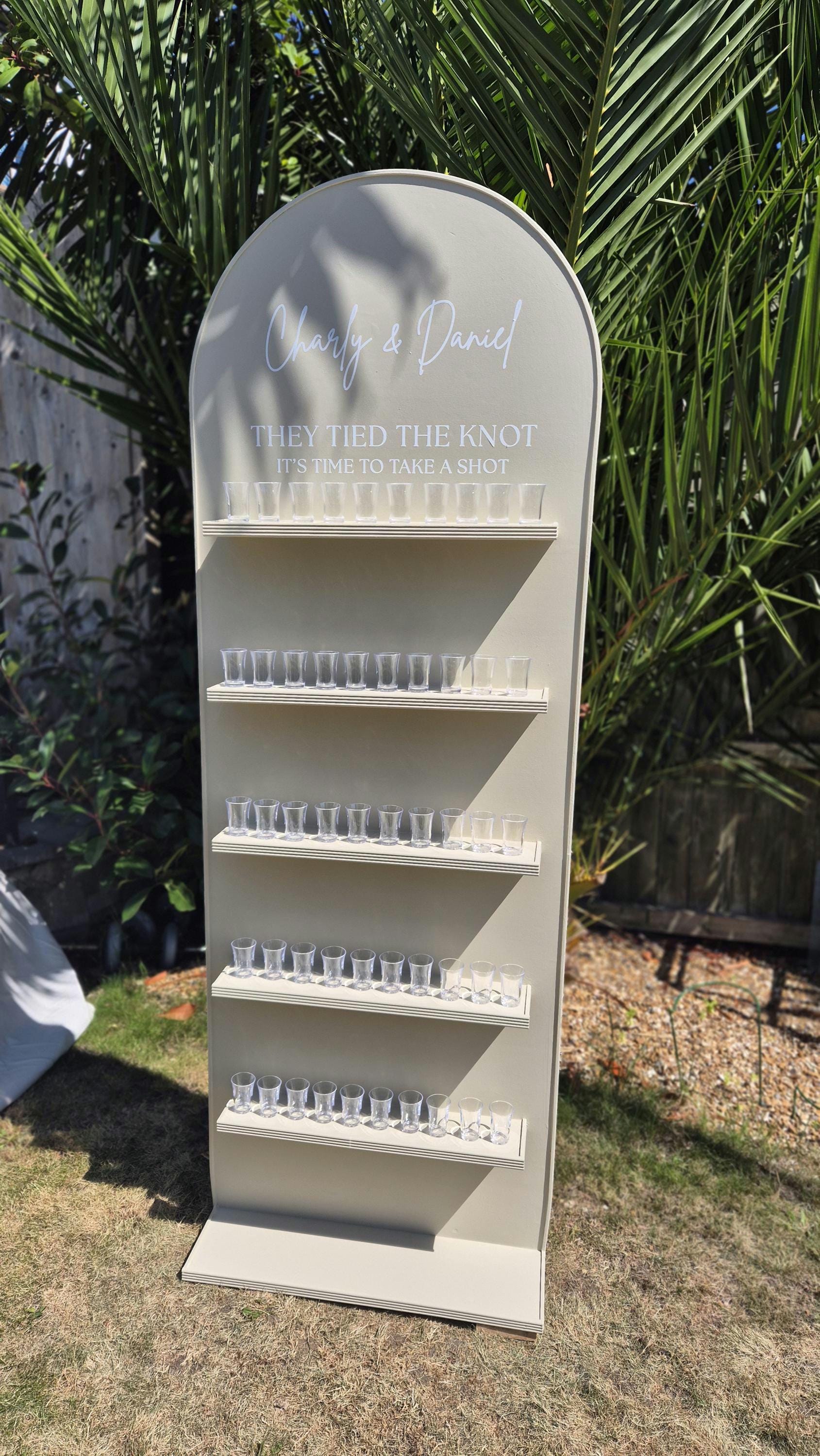 full front view of a wedding shot wall outside in a garden party setting with glasses