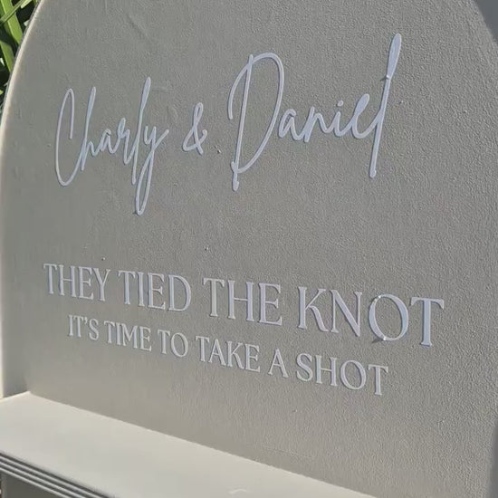 close up of the top section of a wedding wall, showing the graphics on the wall "They tied the knot its time to take a shot"