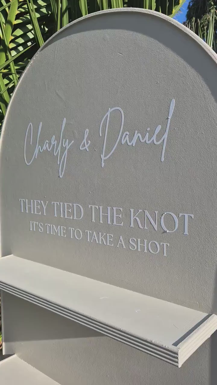 close up of the top section of a wedding wall, showing the graphics on the wall "They tied the knot its time to take a shot"